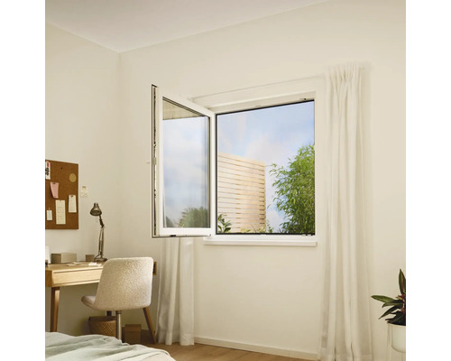 Otvorené otočné okno v svetlej miestnosti s písacím stolom a výhľadom do záhrady.