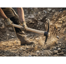 Muž používa krompáč na kopanie v zemi