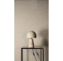 Stolná lampa s polguľovitým tienidlom a kužeľovitou kamennou základňou na čiernom stolíku pred štruktúrovanou stenou.