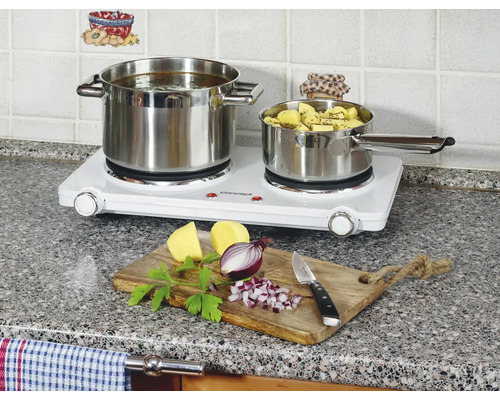 Dvojitá varná doska s dvoma nerezovými hrncami a ingredienciami na doske na krájanie