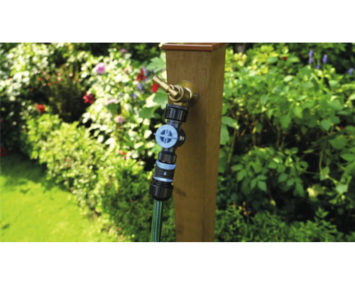 Záhradná scéna s vodovodným kohútikom na drevenom stĺpiku a pripojenou záhradnou hadicou