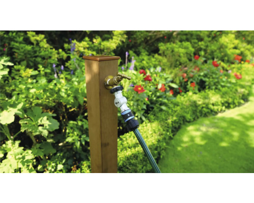 Záhradná scéna s vodovodným kohútikom a záhradnou hadicou na drevenom stĺpiku