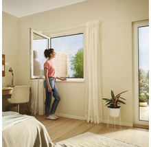 Svetlá spálňa s výklopným oknom a ženou, ktorá sa pozerá von