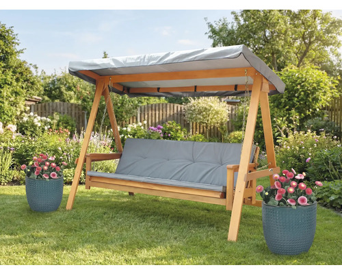 Drevená hojdačka so sivými podložkami a strieškou v záhrade