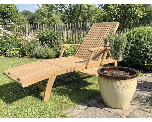 Drevené záhradné ležadlo vedľa kvetináča s rastlinou v záhrade