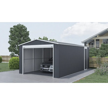 Veľká kovová garáž v antracitovej farbe s bielym rámom a sedlovou strechou, s bočným vchodom a zaparkovaným autom na dláždenej príjazdovej ceste.