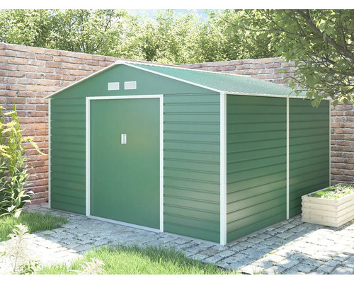 Kovový záhradný domček v zelenej farbe so sedlovou strechou a posuvnými dverami, umiestnený v záhrade na dlažbe pred tehlovým múrom.