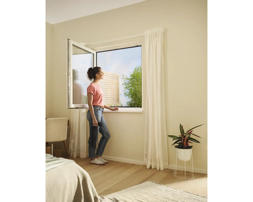 Žena pri otvorenom okne so sieťou proti hmyzu v spálni