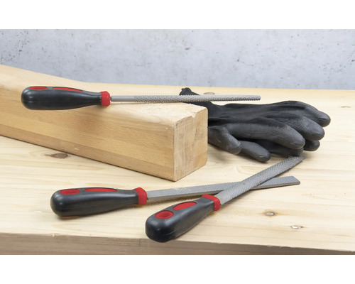 Drevený blok, rukavice a rôzne pilníky na drevenom povrchu.