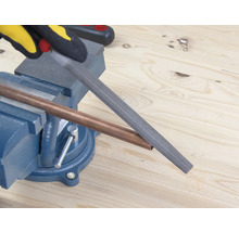 Medená rúrka opracovávaná pilníkom, ktorý je upevnený v zveráku.