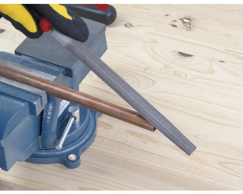 Medená rúrka opracovávaná pilníkom, ktorý je upevnený v zveráku.