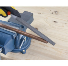 Medená rúrka je opracovávaná pilníkom upnutým v zveráku.