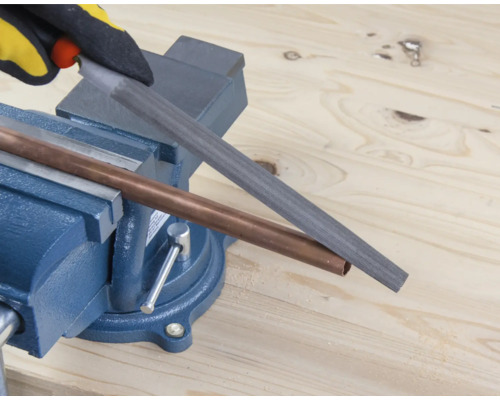 Medená rúrka je opracovávaná pilníkom upnutým v zveráku.