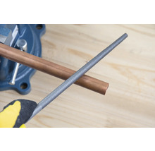 Medená rúrka v zveráku s kovovým pilníkom