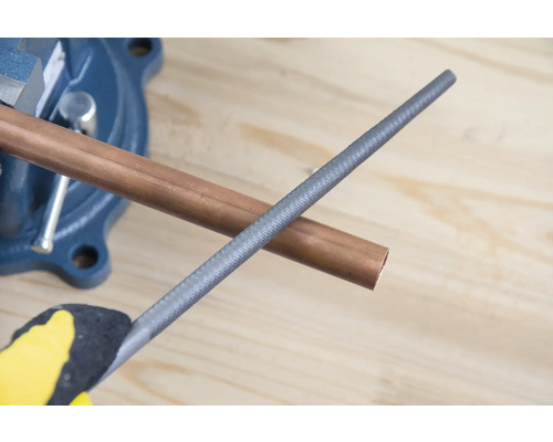 Medená rúrka v zveráku s kovovým pilníkom