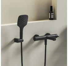 Moderný sprchový set v matnej čiernej farbe s obdĺžnikovou ručnou sprchou a valcovou nástennou batériou v minimalistickej kúpeľni.