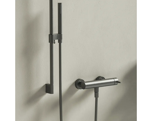 Moderný sprchový systém s ručnou sprchou, sprchovou tyčou a termostatickou batériou z kartáčovaného tmavého kovu.