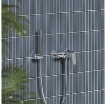 Chrómová páková vaňová batéria s tyčovou ručnou sprchou na moderne obloženej stene.