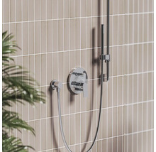 Moderná podomietková sprchová batéria v chróme s pákovým ovládaním, nástennou prípojkou a ručnou sprchou na tyči pred obloženou stenou.