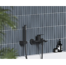 Čierna nástenná vaňová batéria s ručnou sprchou na vertikálne obkladanej stene v modernej kúpeľni.