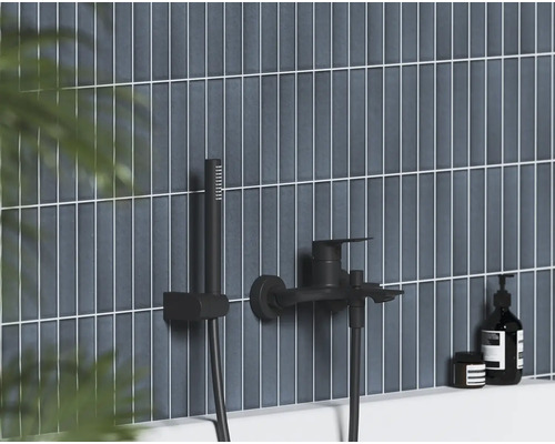 Čierna nástenná vaňová batéria s ručnou sprchou na vertikálne obkladanej stene v modernej kúpeľni.