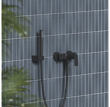 Čierna nástenná vaňová batéria s ručnou sprchou a držiakom na stene s vertikálnymi obkladmi.