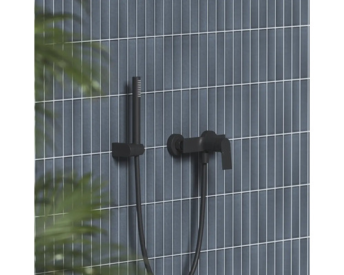 Čierna nástenná vaňová batéria s ručnou sprchou a držiakom na stene s vertikálnymi obkladmi.