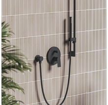 Čierna podomietková sprchová batéria s ručnou sprchou na obloženej stene v modernej kúpeľni.