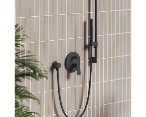 Čierna podomietková sprchová batéria s ručnou sprchou na obloženej stene v modernej kúpeľni.