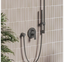 Čierna podomietková sprchová batéria s pákou, ručnou sprchou na tyči a hadicou pred obkladom.