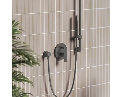 Čierna podomietková sprchová batéria s pákou, ručnou sprchou na tyči a hadicou pred obkladom.