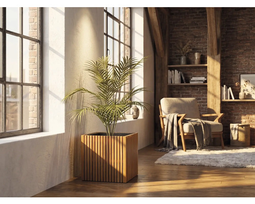 Štvorcový drevený kvetináč s vertikálnymi lamelami a izbovou rastlinou vo svetlej obývacej izbe s tehlovou stenou a veľkými oknami.