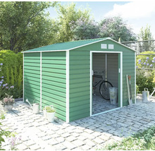 Zelený kovový záhradný domček so sedlovou strechou a posuvnými dverami na dlažbe v záhrade, s bicyklom vo vnútri a záhradným náradím vonku.