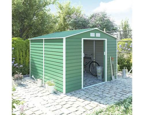 Zelený kovový záhradný domček so sedlovou strechou a posuvnými dverami na dlažbe v záhrade, s bicyklom vo vnútri a záhradným náradím vonku.