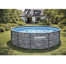 Okrúhly bazén Marimex s kovovým rámom a vonkajším dekorom kameňa na trávniku v presvetlenej záhrade s domom v pozadí.