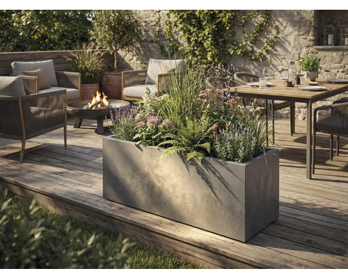 Veľký obdĺžnikový kvetináč v betónovom vzhľade na drevenej terase v moderne navrhnutej záhrade s posedením a ohniskom.