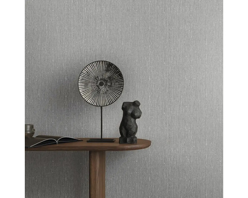 Moderná sivá tapeta s vertikálnou líniovou štruktúrou so vzhľadom ľanu na stene za dreveným stolom s minimalistickou dekoráciou.