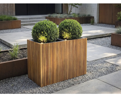 Obdĺžnikový kvetináč z drevených lamiel s dvoma guľatými krušpánmi a integrovaným osvetlením v modernej záhrade so štrkom.