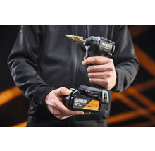 Akumulátorový rázový uťahovák DeWalt Special Edition so stupňovitým vrtákom a 18 Volt akumulátorom v rukách osoby.