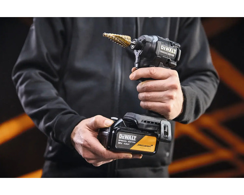 Akumulátorový rázový uťahovák DeWalt Special Edition so stupňovitým vrtákom a 18 Volt akumulátorom v rukách osoby.