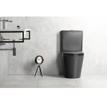 Moderná kúpeľňa s čiernou stojacou toaletou s nádržkou, bielym umývadlom s čiernym kovovým rámom a dekoratívnymi hodinami.