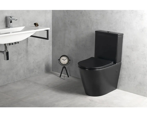 Moderná kúpeľňa s čiernym stojacim WC s nádržkou, bielym nástenným umývadlom s chrómovou batériou a sivou dlažbou v betónovom vzhľade.