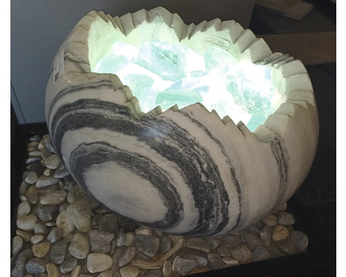 Dekoratívna lampa v tvare rozbitého vajíčka z mramorovaného kameňa, plnená svietiacimi sklenenými kameňmi na okruhliakoch.