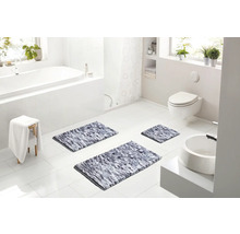 Svetlá moderná kúpeľňa s bielou vaňou, toaletou a tromi sivými melírovanými kúpeľňovými predložkami na bielej dlažbe.