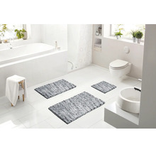 Svetlá moderná kúpeľňa s bielou vaňou, závesnou toaletou, umývadlom a tromi sivými kúpeľňovými predložkami na podlahe.