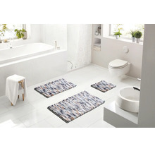 Svetlá kúpeľňa s vaňou, toaletou a umývadlom, vybavená tromi viacfarebnými kúpeľňovými predložkami rôznych veľkostí.