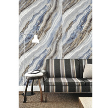 Vliesová tapeta s diagonálnym mramorovým vzorom v modrej a sivej farbe za pruhovanou pohovkou a stojacou lampou v obývacej izbe.