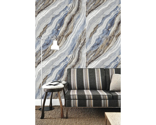 Vliesová tapeta s diagonálnym mramorovým vzorom v modrej a sivej farbe za pruhovanou pohovkou a stojacou lampou v obývacej izbe.