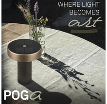 Solárna stolná lampa POGA na záhradnom stole s obrusom vedľa sklenenej vázy s kvetmi.