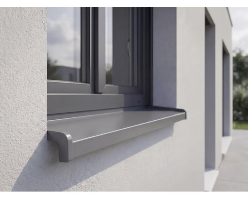 Vonkajší hliníkový parapet inštalovaný na omietnutej fasáde pod oknom.